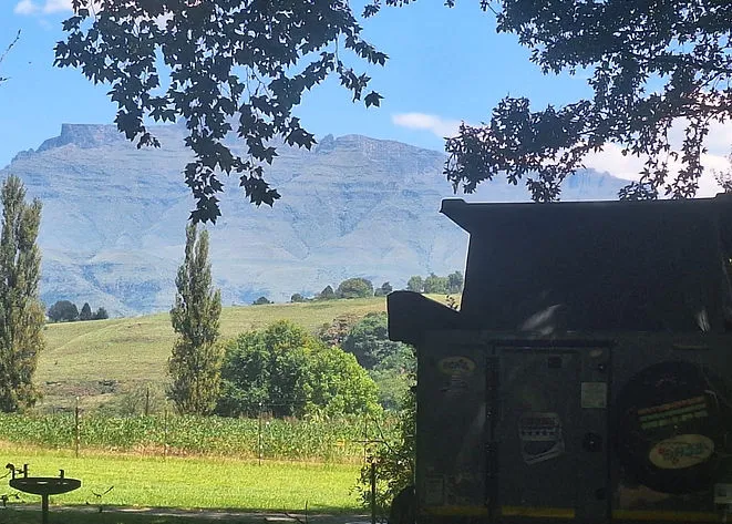 A mountain view with trees and a building in the foreground