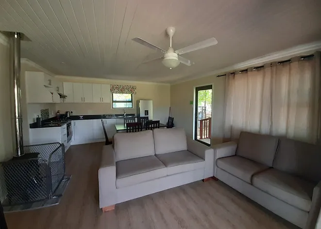 Openplan living room with kitchen sofas ceiling fan and large windows