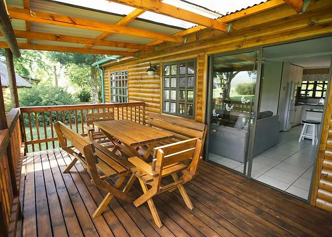 Wooden deck with table and chairs outside a log cabin with open sliding doors