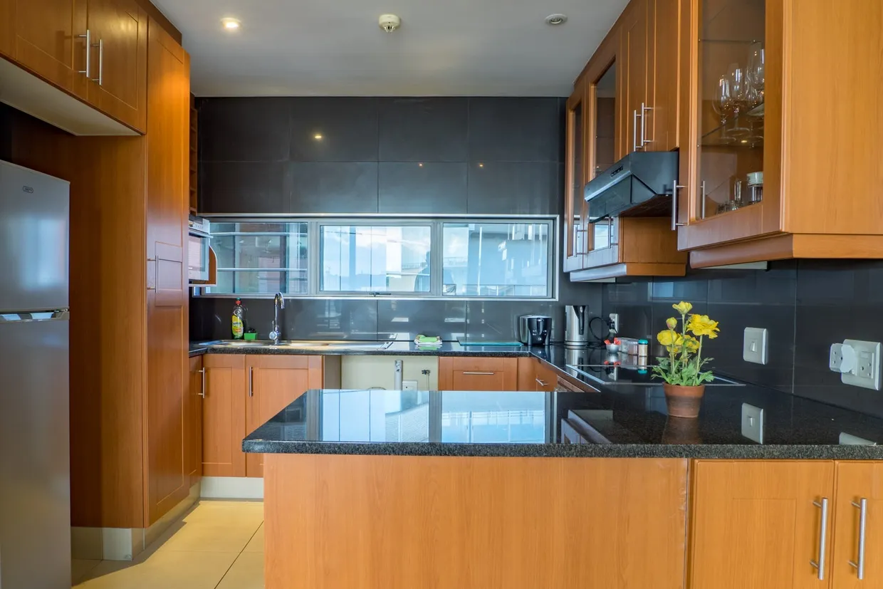 Modern kitchen with wooden cabinets black countertops and large windows