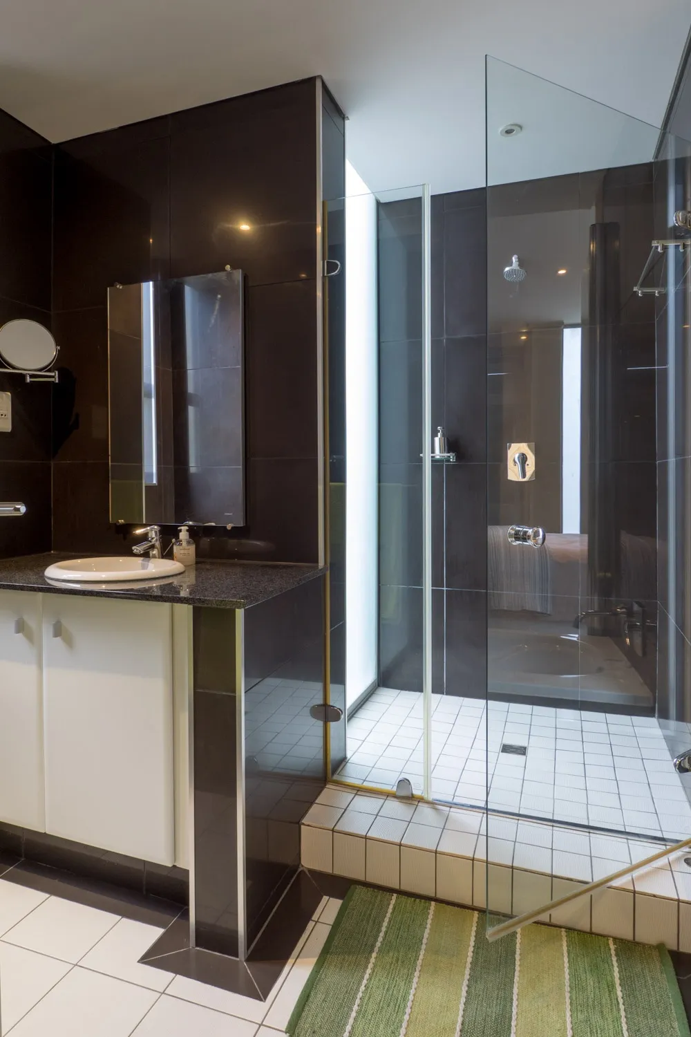 Modern bathroom with black tiles glass shower and white cabinet
