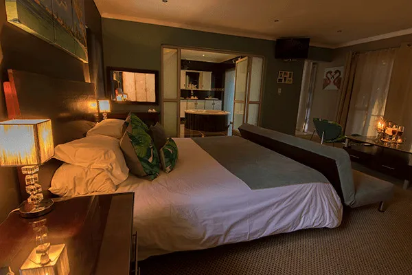 Cozy bedroom with a large bed dim lighting and a view of the bathroom