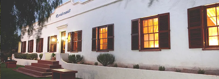 White building with lit windows and wooden shutters evening setting Kronendal sign