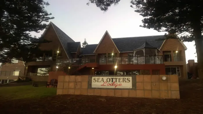 Sea Otters Lodge building with sign in front surrounded by trees