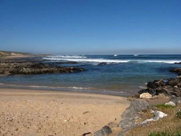 Sandy beach with rocky outcrops and waves crashing in the distance