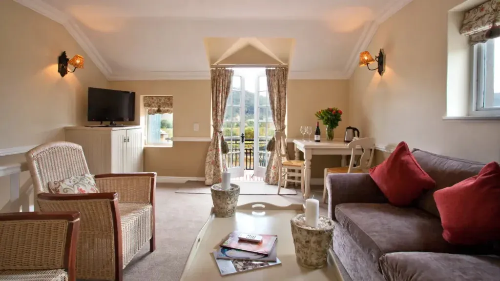 Cozy living room with sofa chairs TV and view of garden through French doors