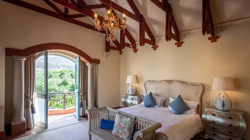Bedroom with a large bed open balcony doors and a chandelier