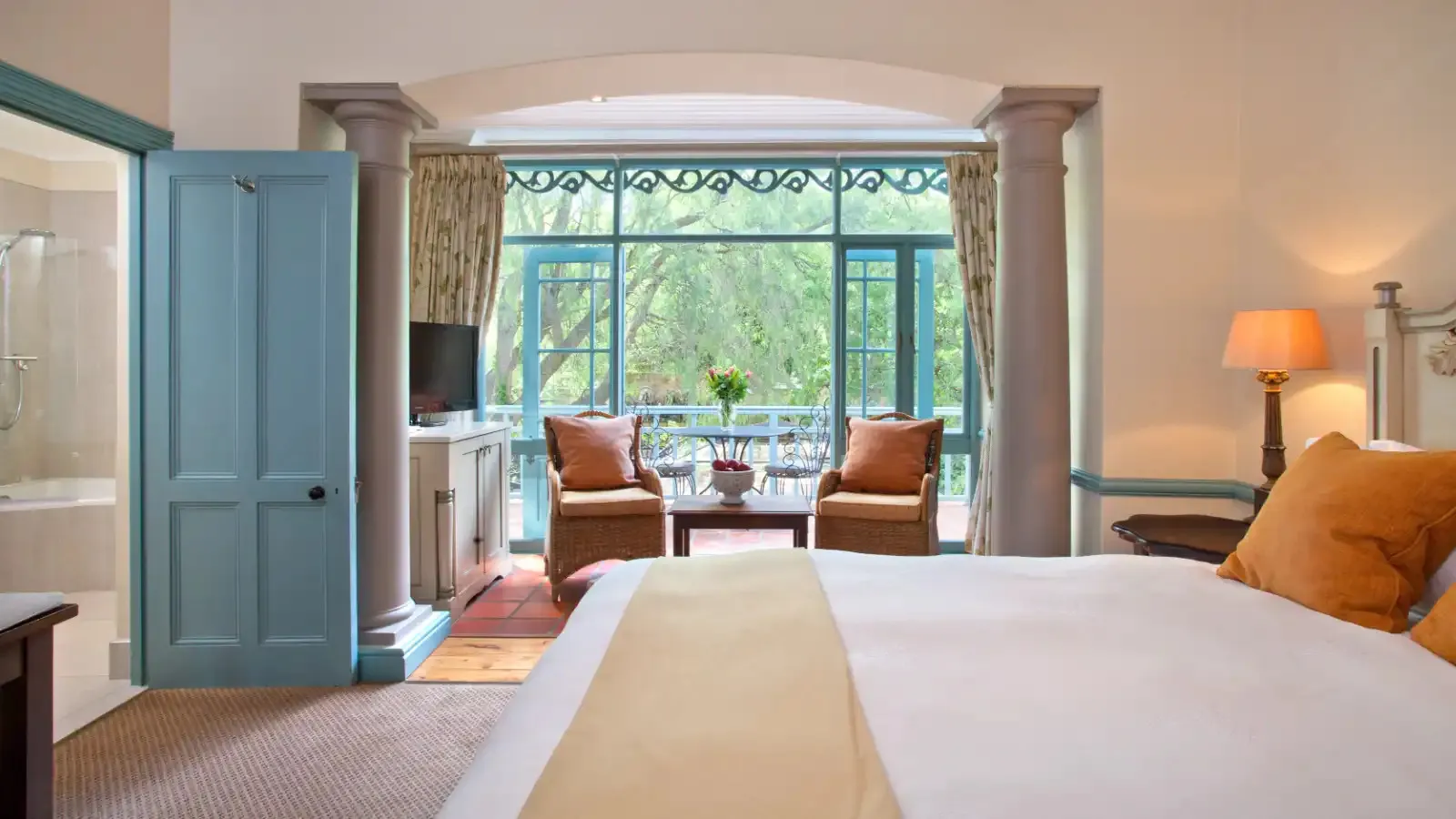 Hotel room with a bed seating area and large windows overlooking a garden