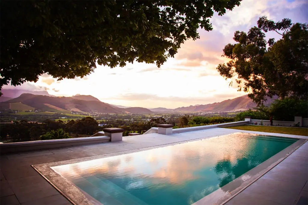 Swimming pool with mountain view at sunset framed by trees