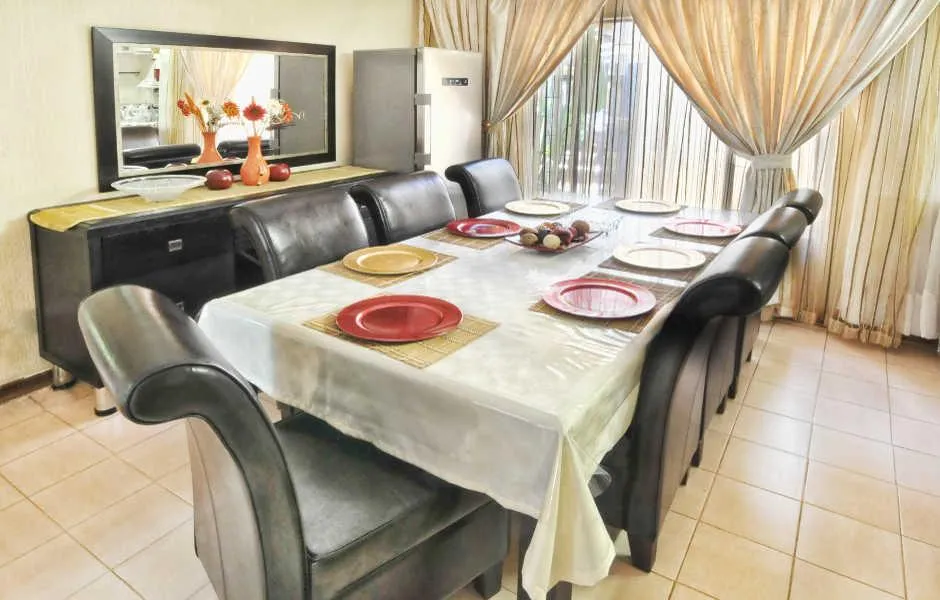Dining room with table set for eight large mirror and curtains