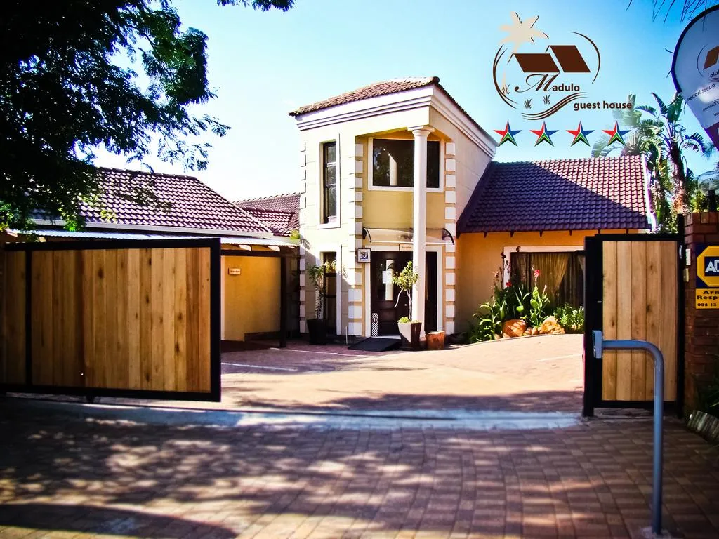 Guest house with wooden gate brick driveway and tropical landscaping