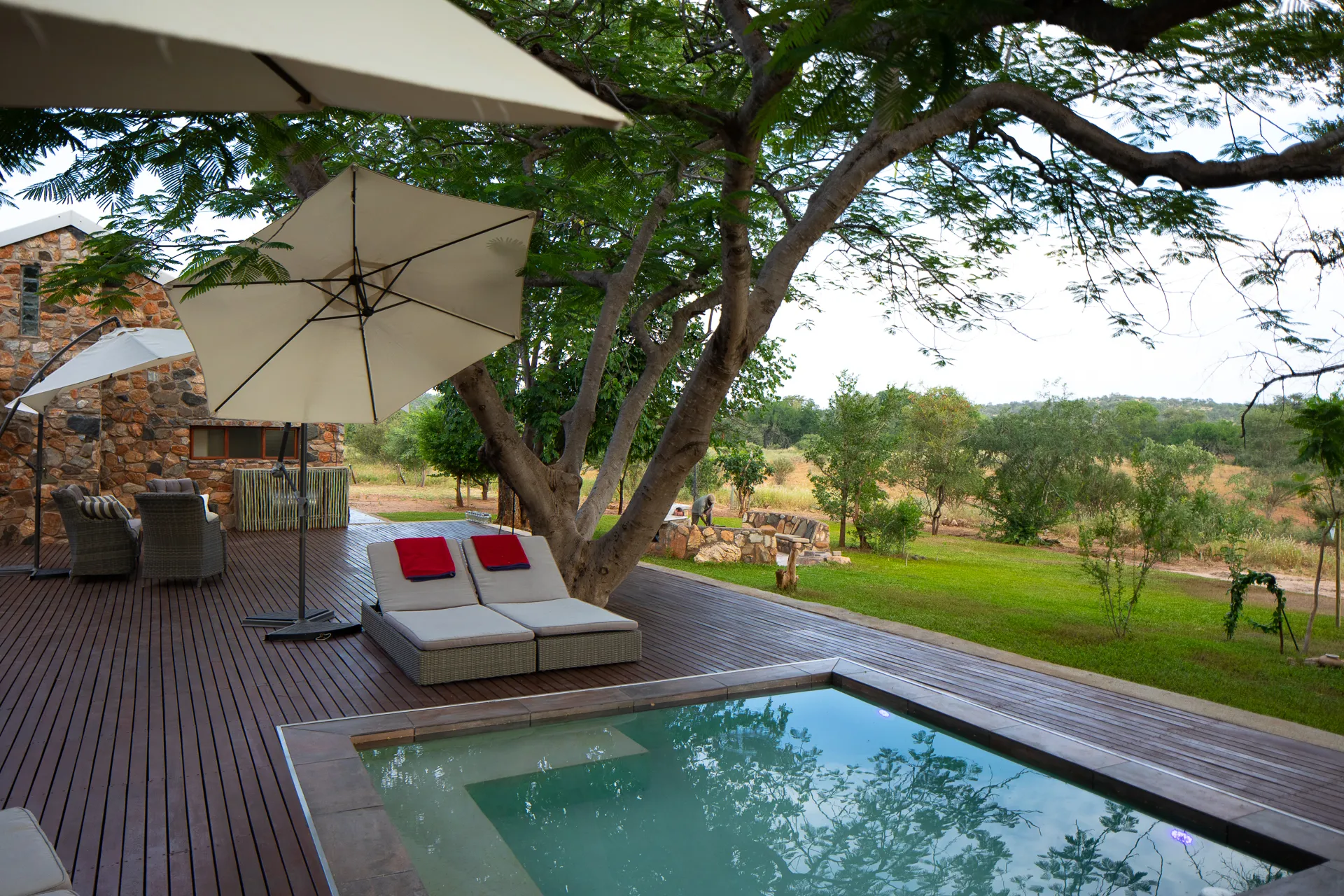 Outdoor lounge area with pool umbrellas and trees overlooking a grassy landscape