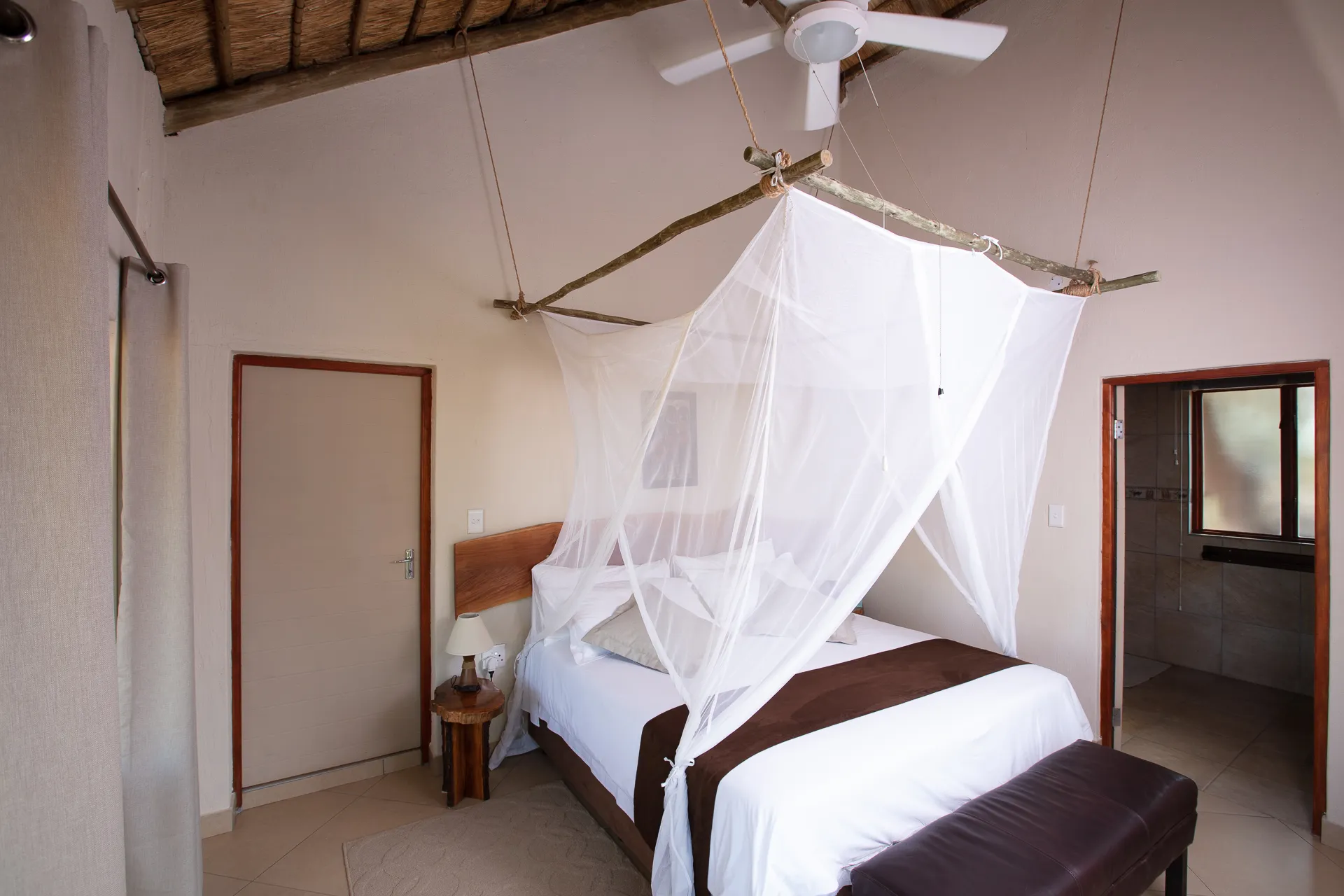 Bedroom with a large bed mosquito net and wooden ceiling