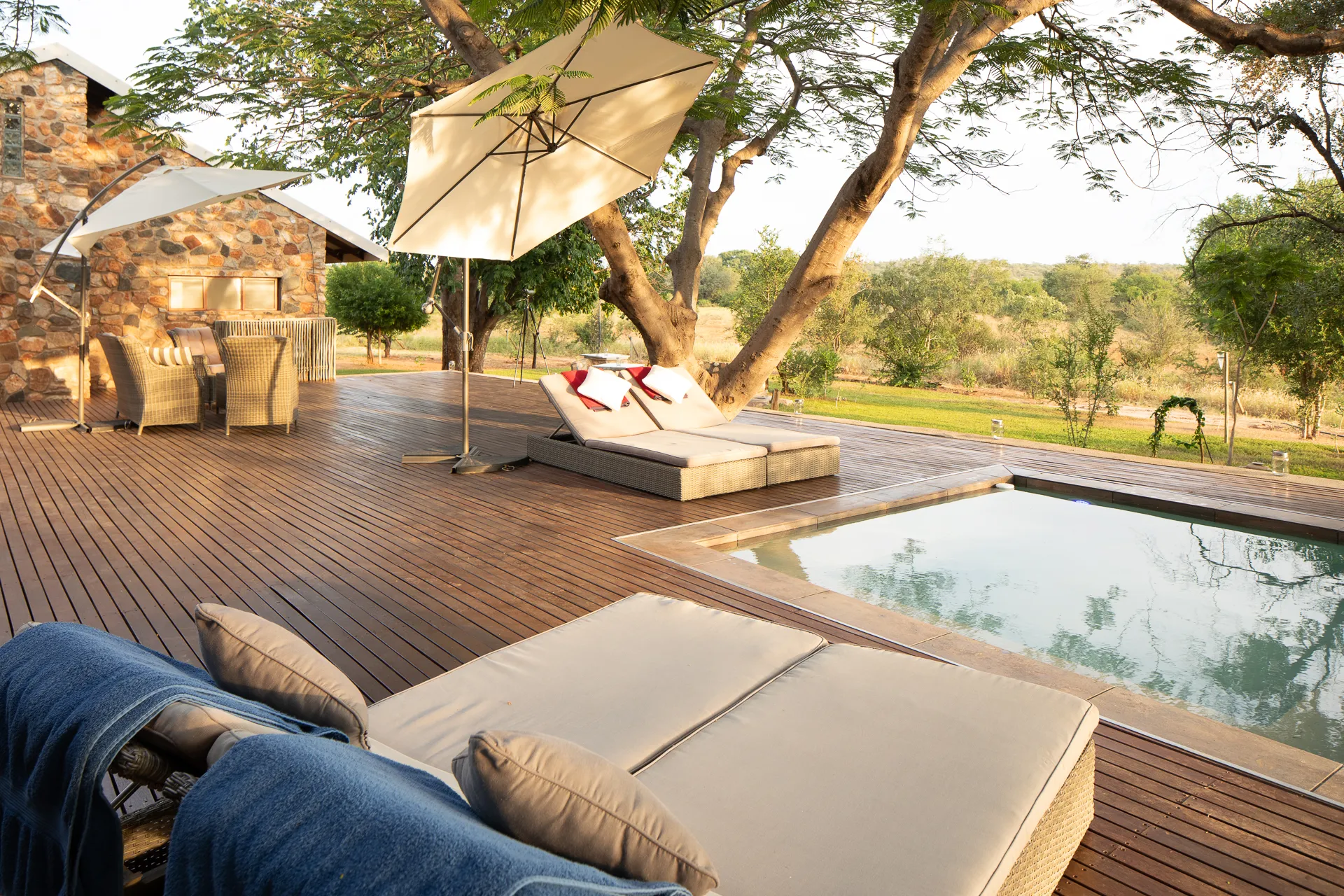 Wooden deck with lounge chairs umbrellas and a pool overlooking a natural landscape