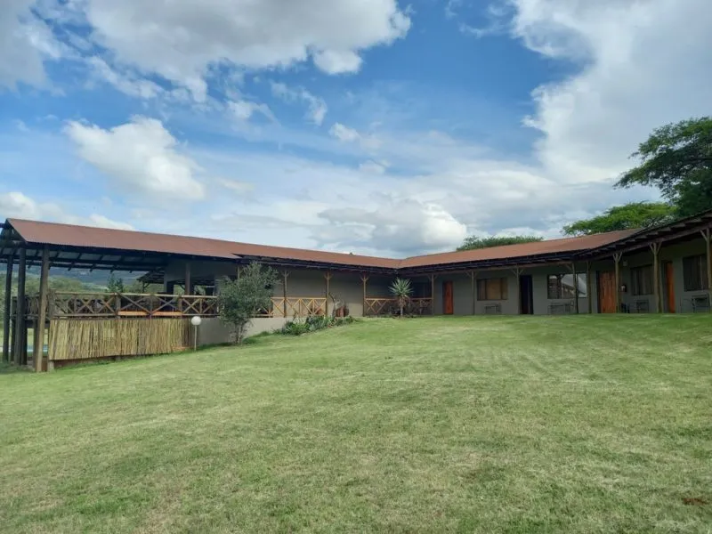 Singlestory building with a veranda surrounded by green grass and trees