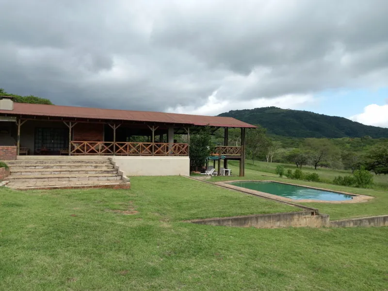 House with a veranda and swimming pool in a rural setting with hills