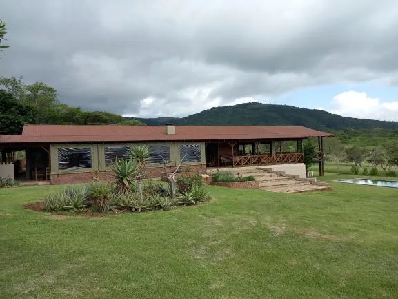 Country house with garden pool and mountain backdrop under cloudy sky