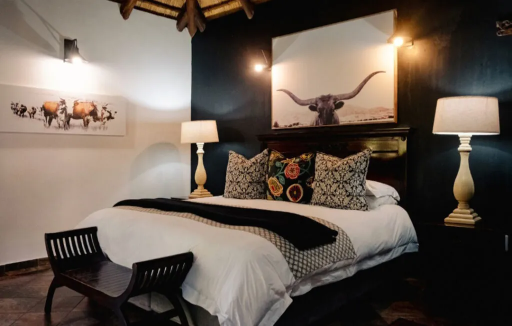 Bedroom with a large bed black walls and cowthemed artwork above the headboard