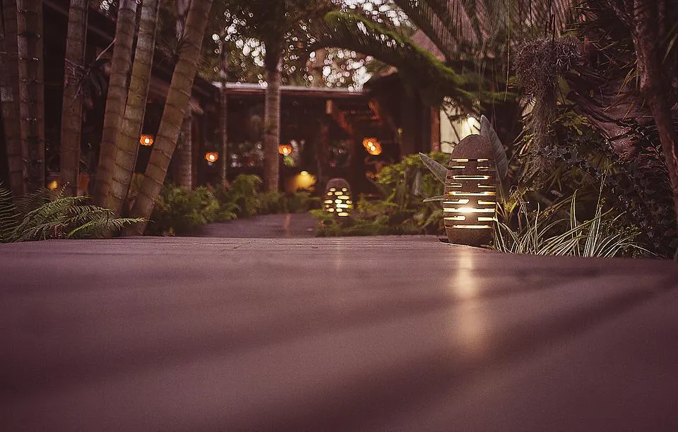 Wooden pathway through a tropical garden with warm lighting in the evening