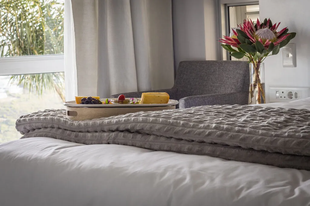 Bed with a tray of food and a vase of flowers on a table