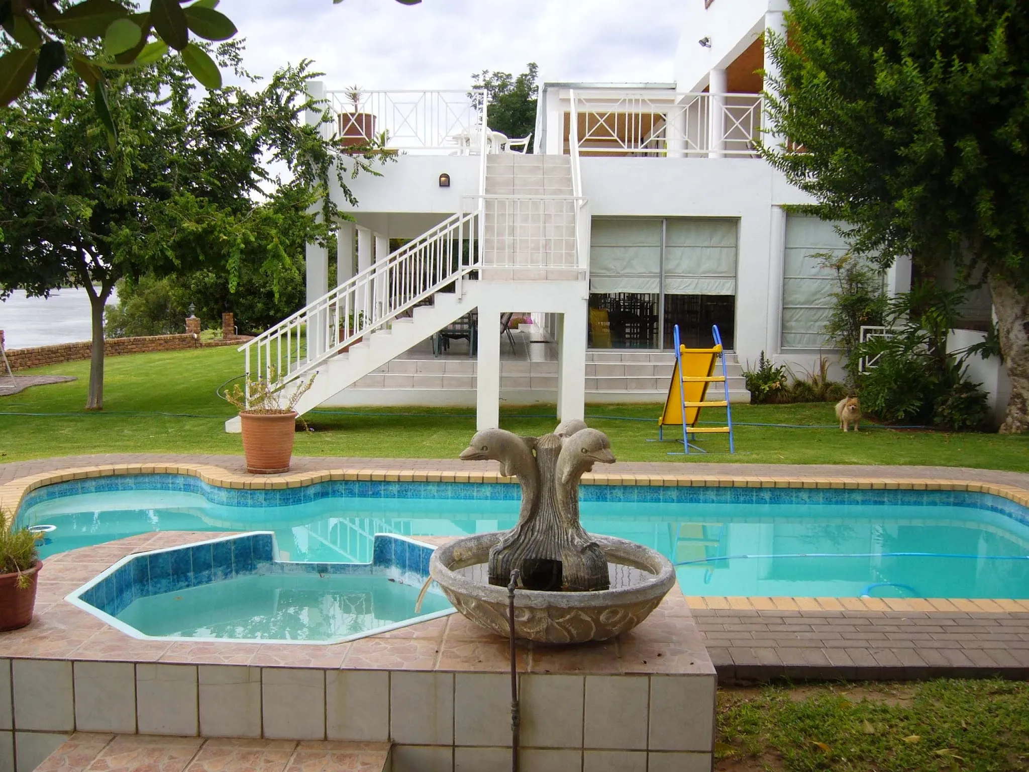 Twostory house with pool slide and garden in a sunny backyard