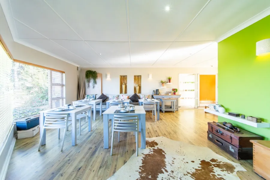 Bright dining area with white chairs tables and green accent wall