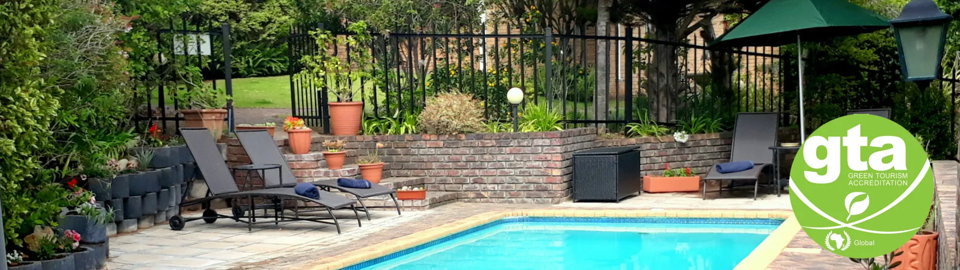 Swimming pool with lounge chairs and potted plants in a fenced garden area
