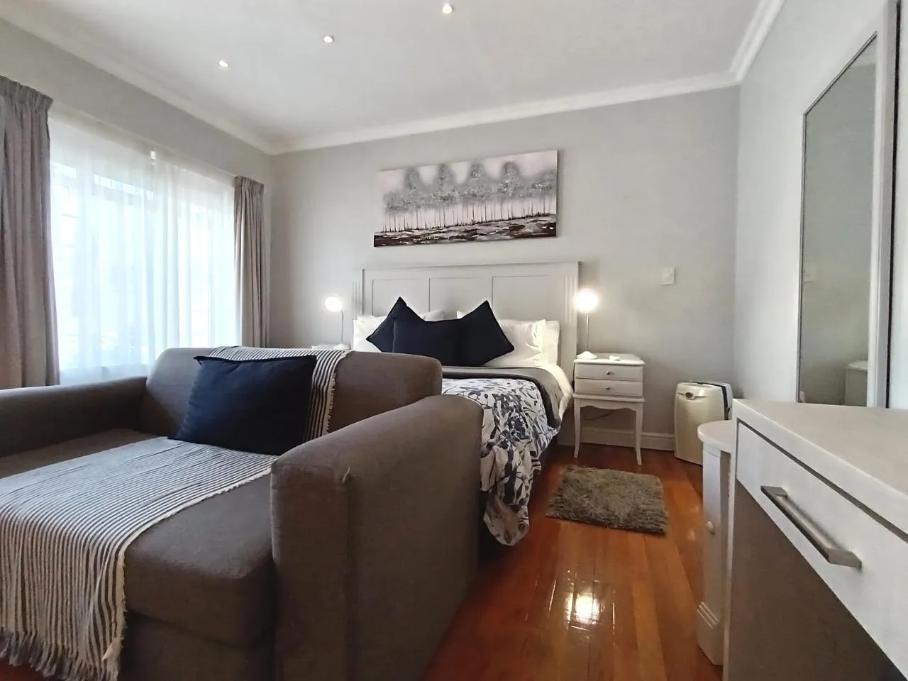 Modern bedroom with bed sofa dresser and wooden floor