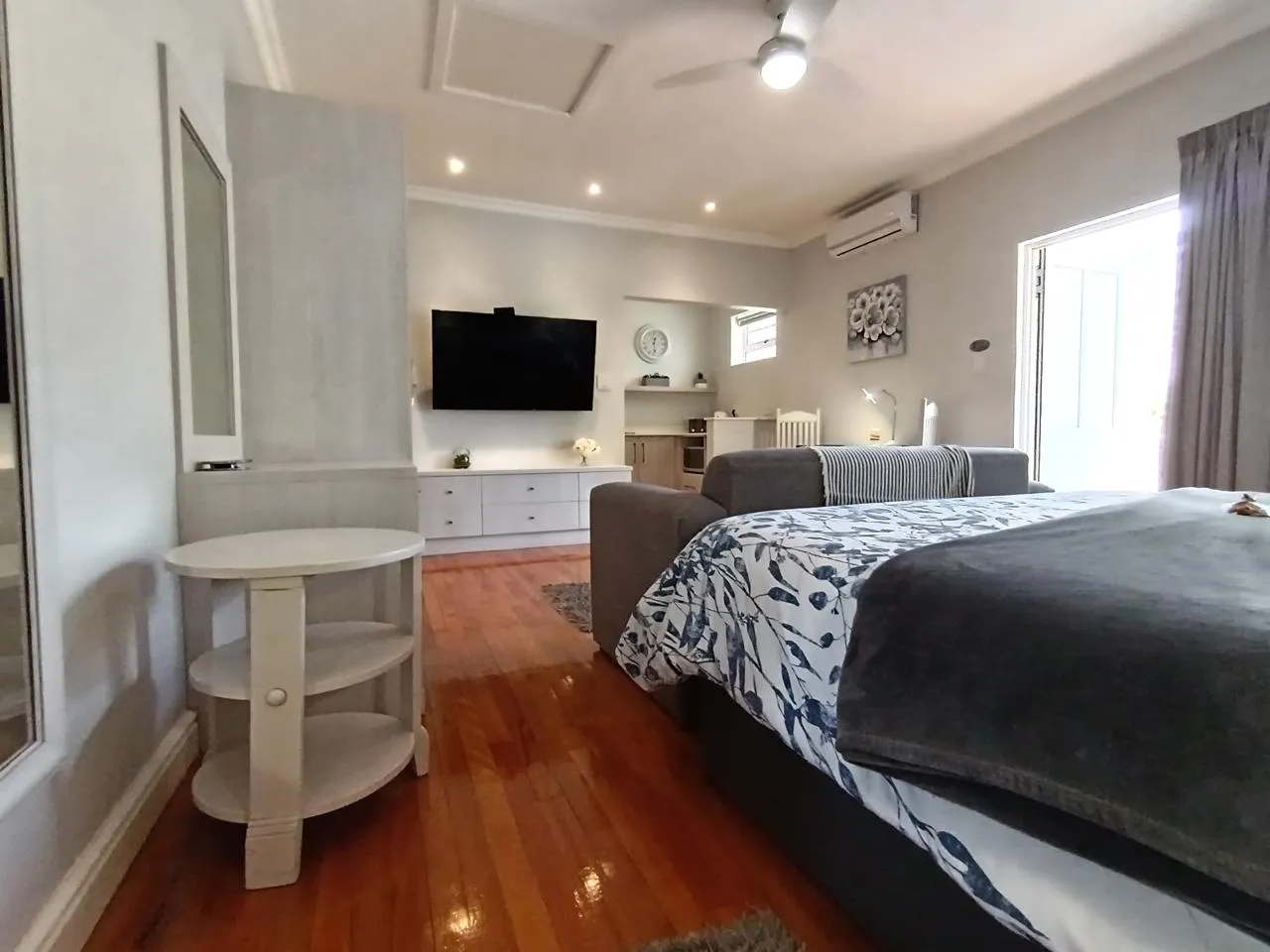 Bedroom with bed TV couch and ceiling fan in a modern setting