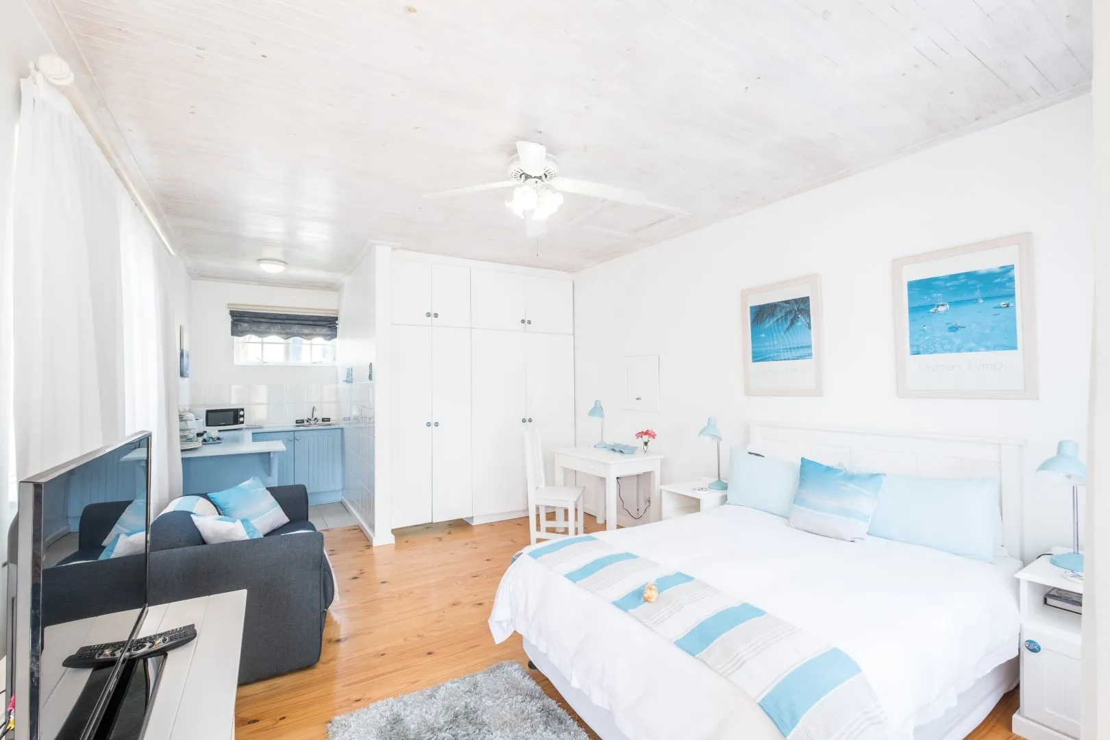 Cozy studio apartment with a bed sofa kitchenette and beachthemed decor