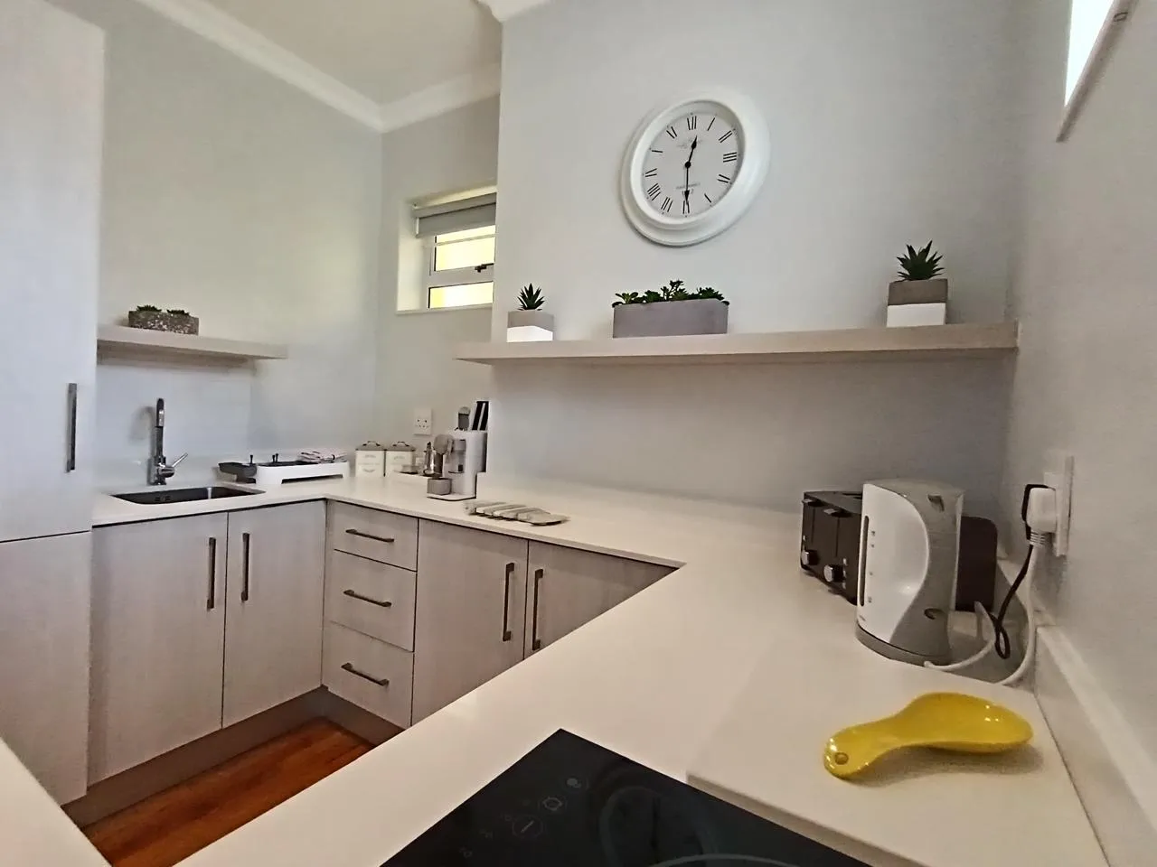 Modern kitchen with white cabinets clock and small appliances on countertops