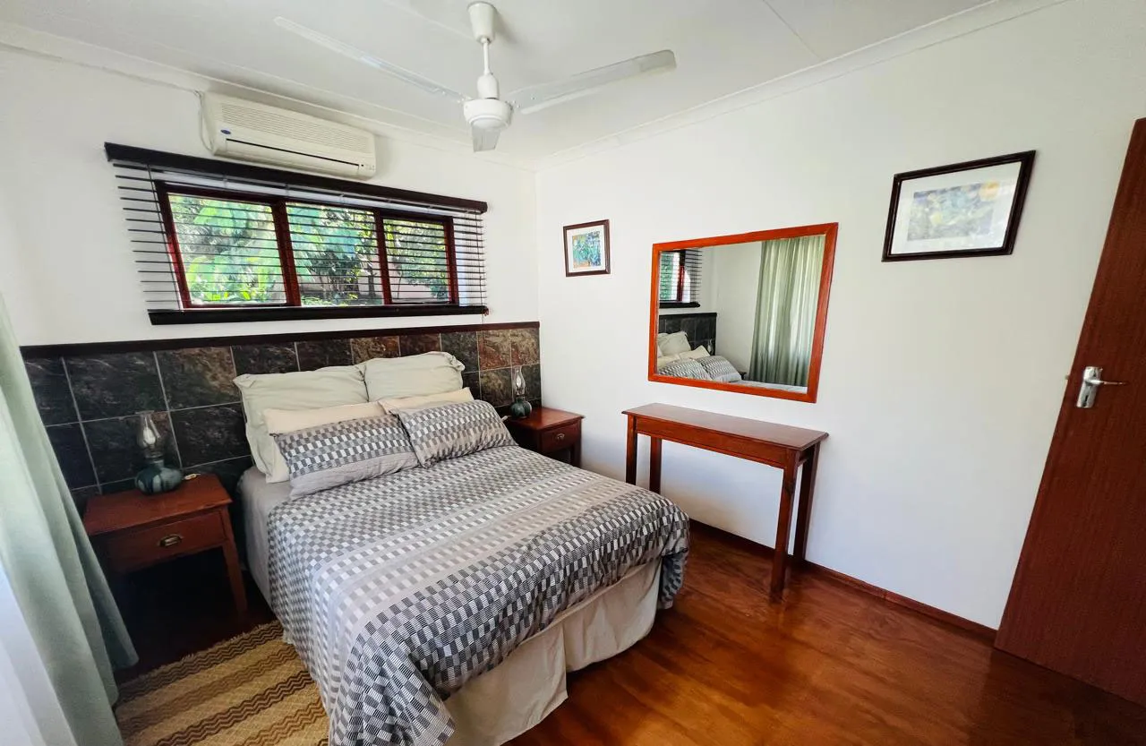 Cozy bedroom with double bed wooden furniture and ceiling fan