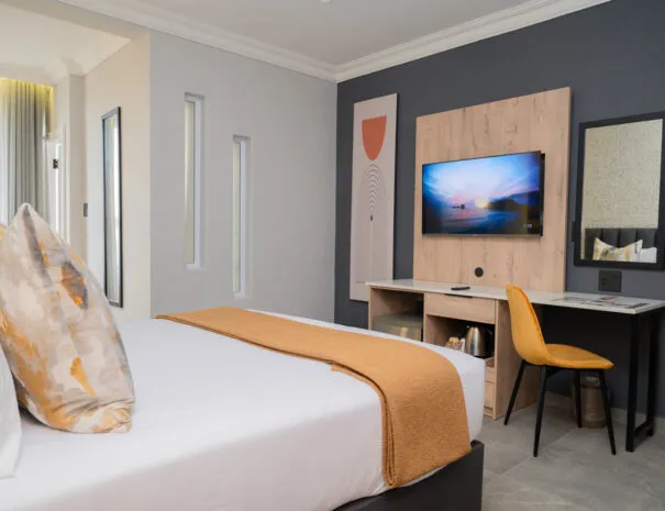 Modern hotel room with bed desk TV and abstract wall art