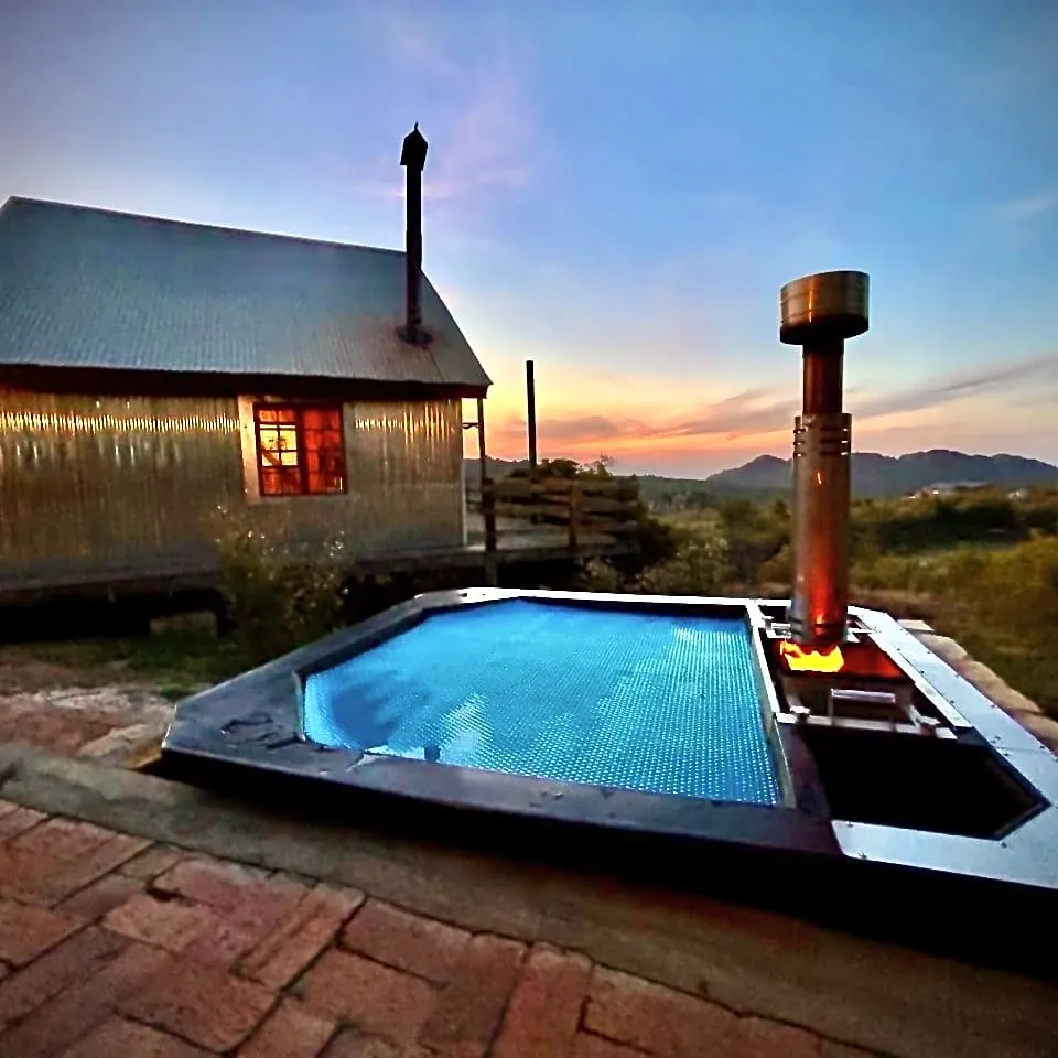 Small pool with heater next to rustic cabin at sunset