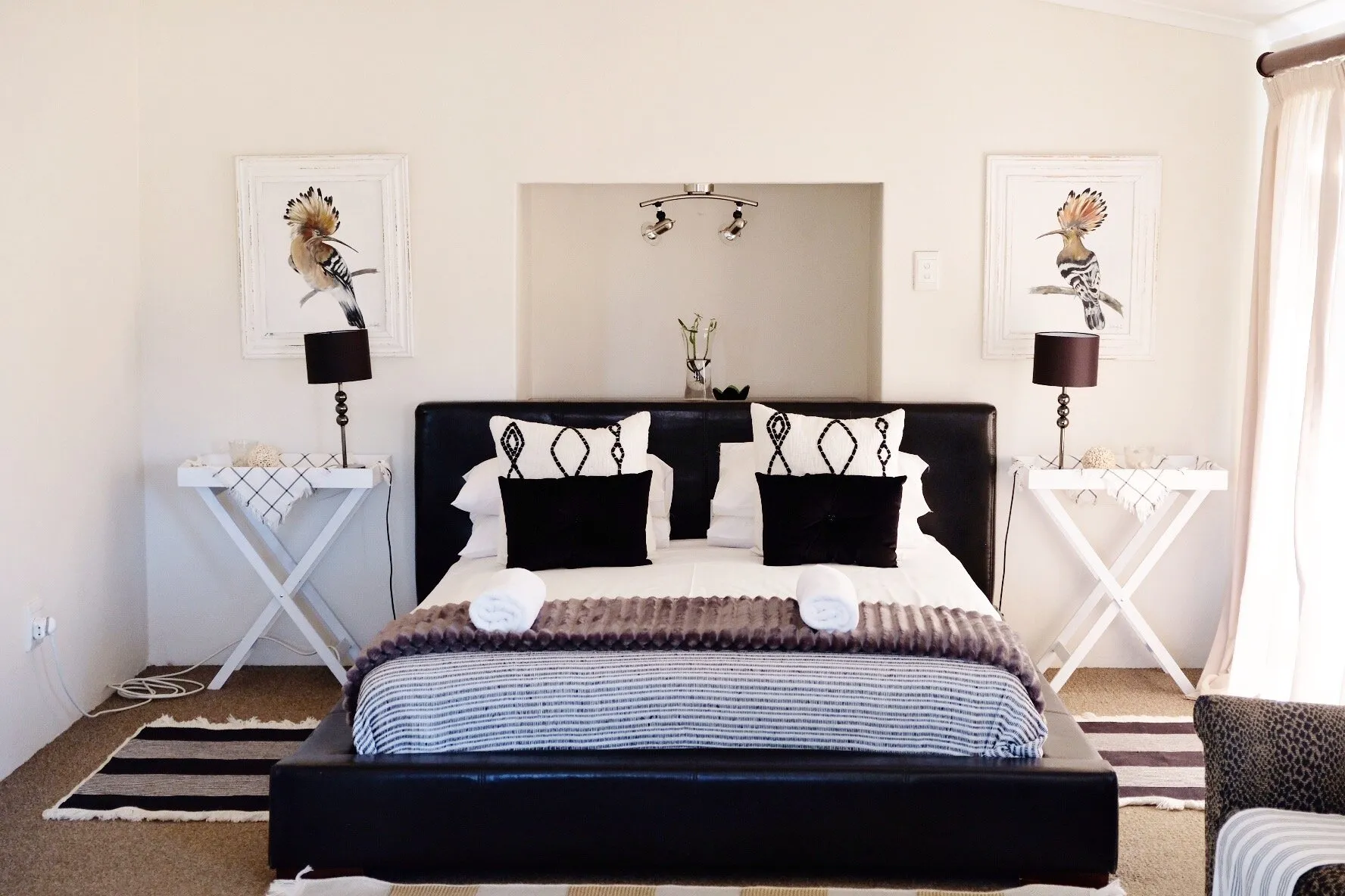 Modern bedroom with a large bed side tables and floral artwork on the walls