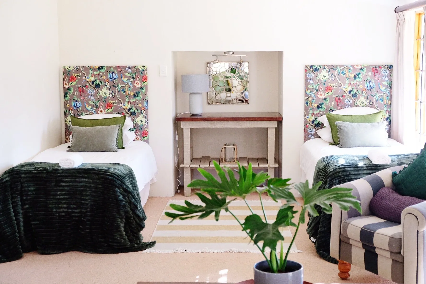Two twin beds with floral headboards in a cozy bedroom with a plant