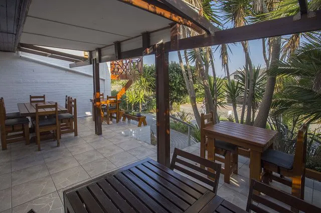 Outdoor seating area with wooden tables and chairs under a covered patio