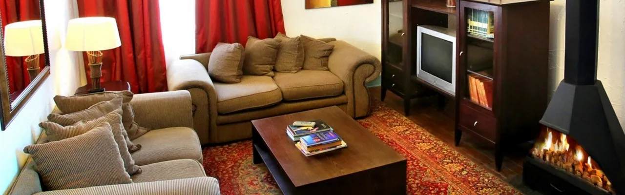 Cozy living room with sofas coffee table TV and fireplace with red curtains