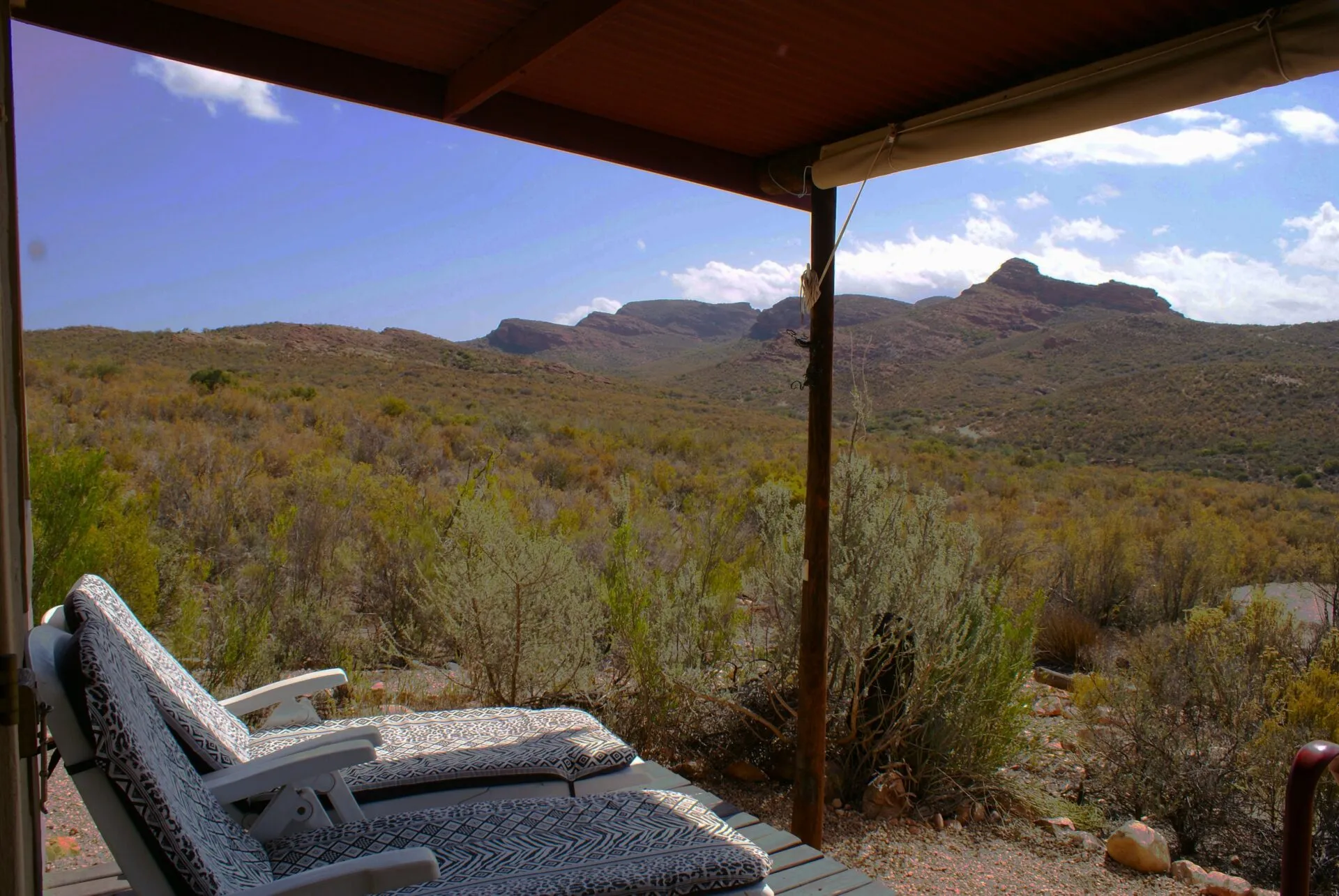 Two lounge chairs on a deck overlooking a scenic mountainous landscape