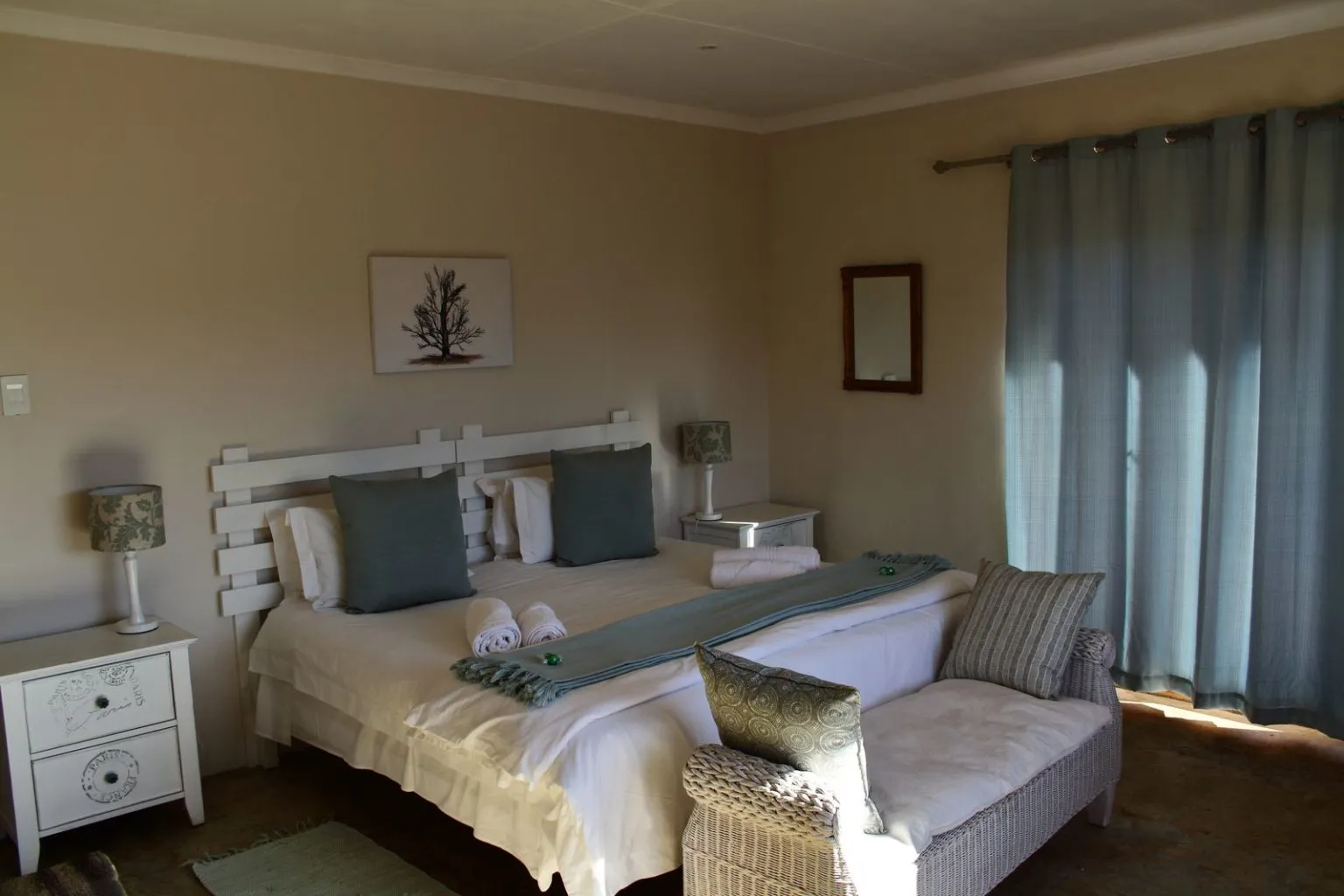 Bedroom with a large bed side tables and a chaise lounge by a window