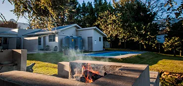 A house with a garden pool and a fire pit in the foreground