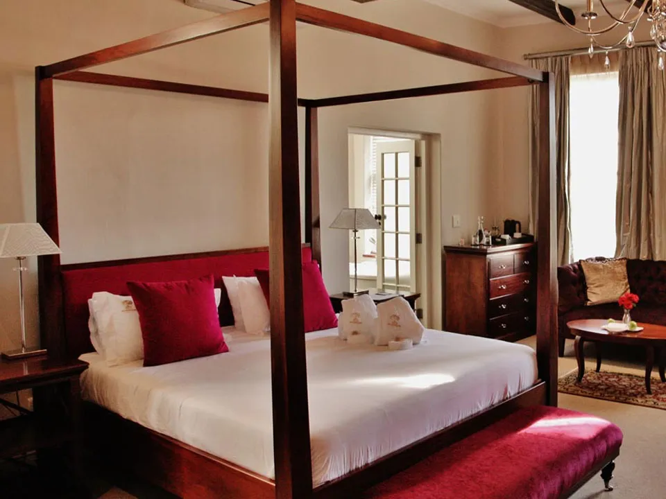 Fourposter bed with red pillows in a wellfurnished bedroom with natural light
