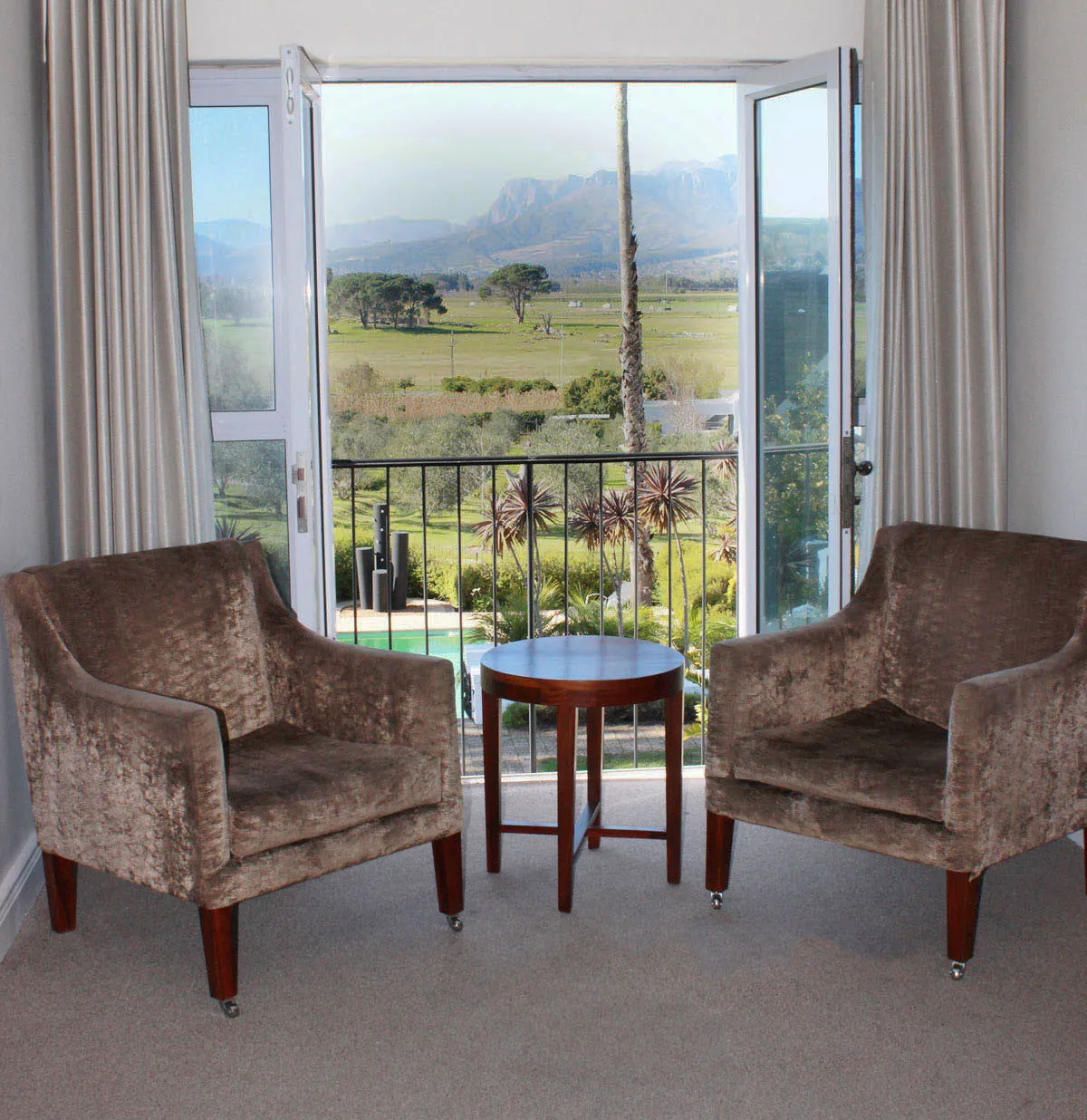 Two armchairs and a small table in front of a large open window