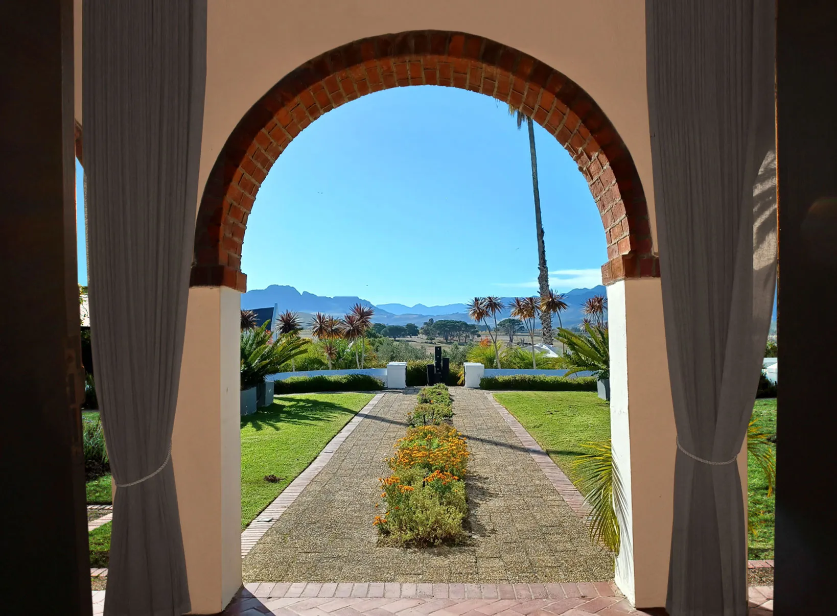 Garden view through an arched doorway with potted plants and distant mountains