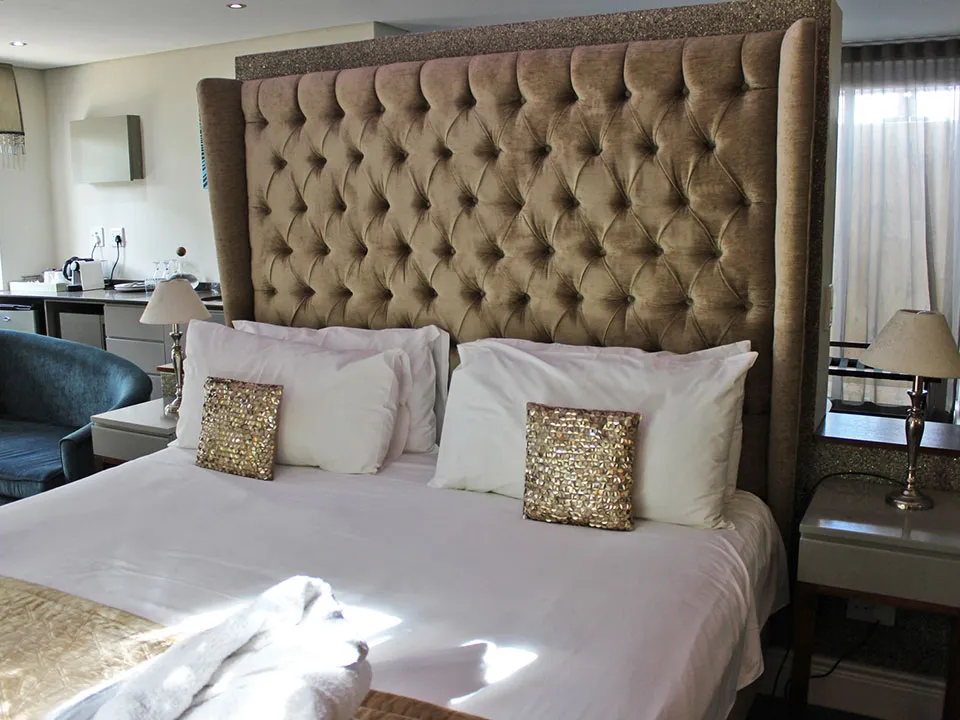 Large bed with upholstered headboard glitter pillows and bedside tables with lamps