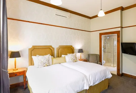 Hotel room with two twin beds nightstand lamp and a visible bathroom