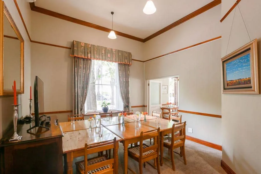 Dining room with wooden table chairs and a window with floral curtains