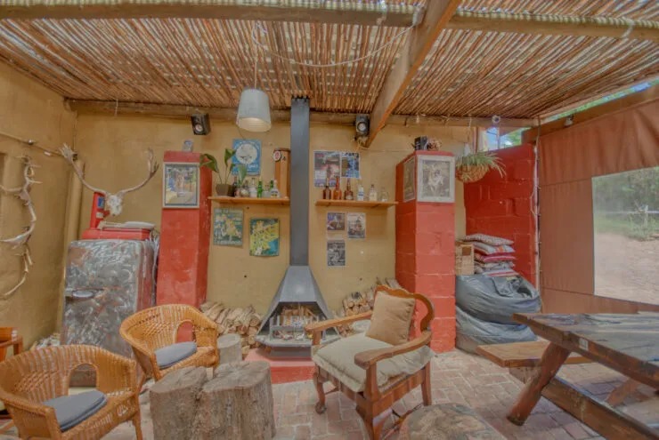 Rustic outdoor seating area with fireplace wicker chairs and wooden ceiling