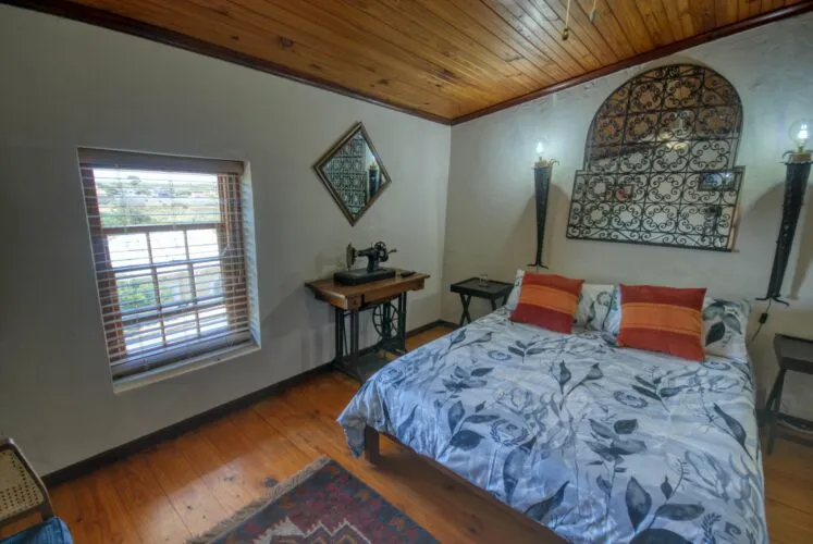 Cozy bedroom with wooden ceiling patterned bedspread and vintage decor