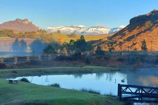 Scenic landscape with pond bridge and snowcapped mountains in the background